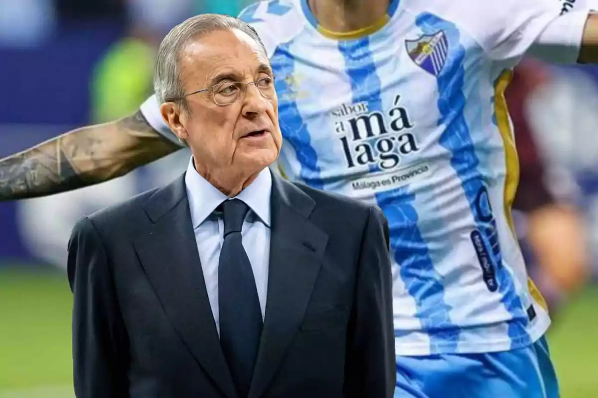 Un hombre mayor con gafas y traje oscuro está frente a un jugador de fútbol con la camiseta del Málaga CF.