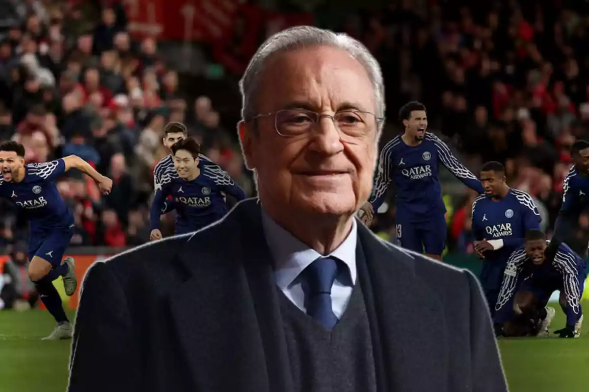 Un hombre mayor con gafas y traje oscuro está en primer plano, mientras que al fondo se ve a un grupo de jugadores de fútbol con uniformes azules celebrando en un estadio lleno de espectadores.