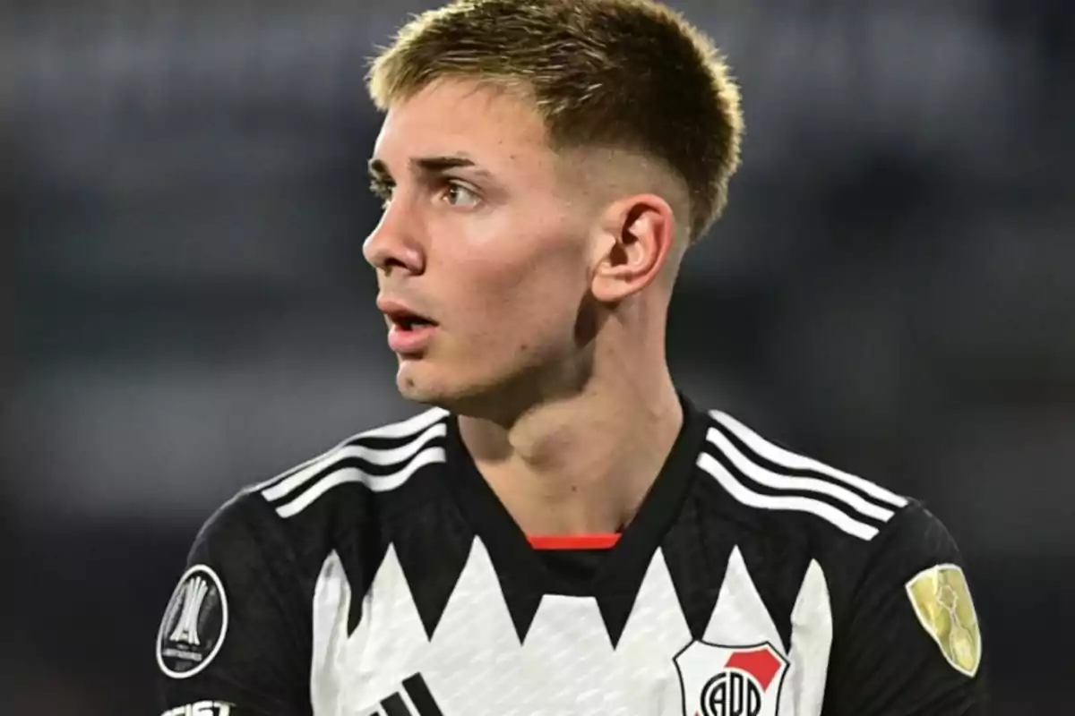 Un jugador de fútbol con uniforme blanco y negro mirando hacia un lado.