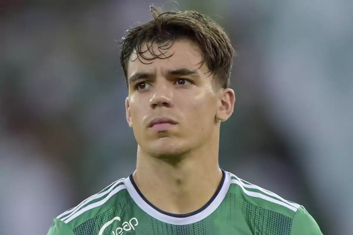 A soccer player in a green jersey looks forward in a stadium.