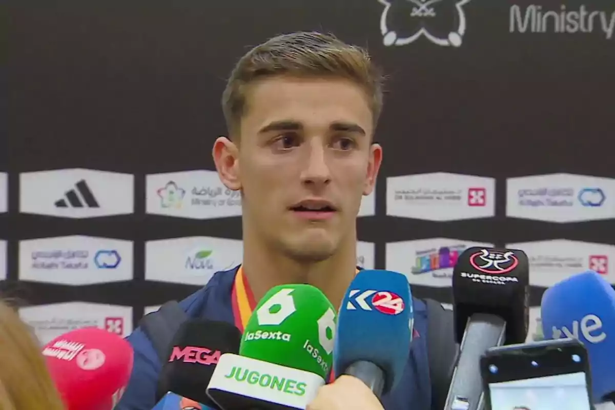 A young athlete is surrounded by microphones from different media outlets during an interview. A young athlete is surrounded by microphones from different media outlets during an interview.