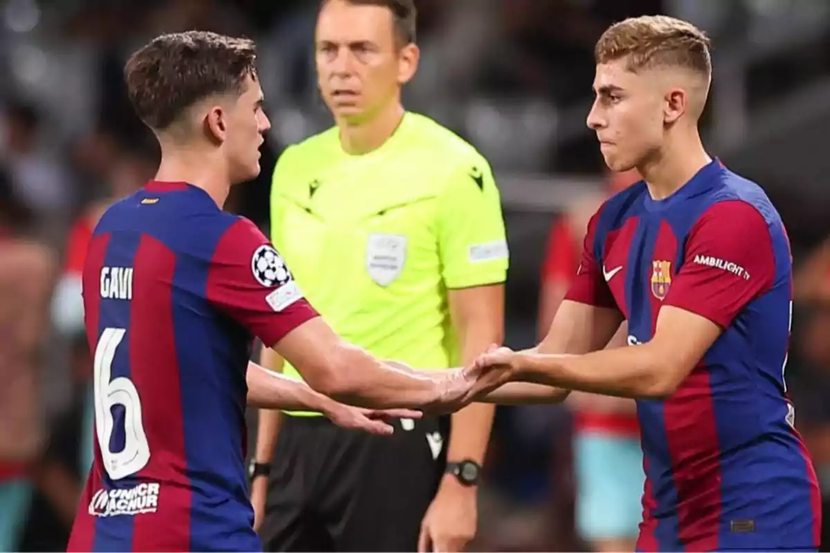 Dos jugadores del Barcelona se dan la mano durante un cambio en un partido de fútbol mientras un árbitro observa en el fondo Dos jugadores del Barcelona se dan la mano durante un cambio en un partido de fútbol mientras un árbitro observa en el fondo