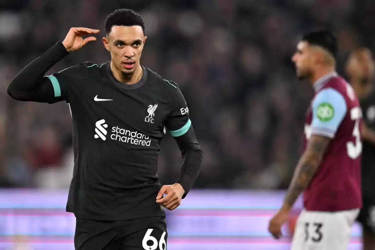 Jugador de fútbol del Liverpool en el campo durante un partido, vistiendo el uniforme negro del equipo.