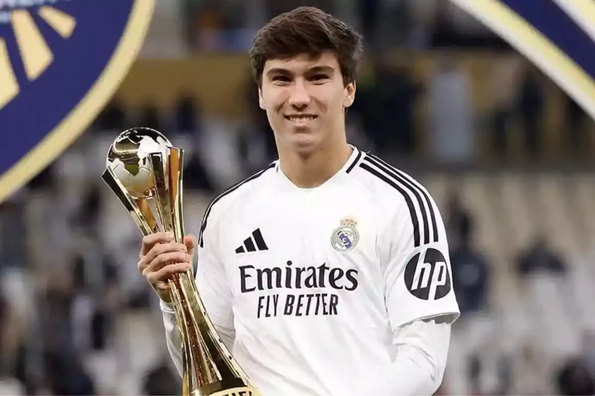 A player in a Real Madrid uniform holds a golden trophy while smiling. A player in a Real Madrid uniform holds a golden trophy while smiling.