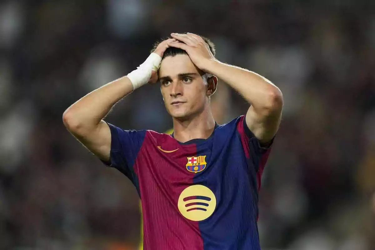 Un jugador de fútbol con la camiseta del FC Barcelona se lleva las manos a la cabeza en el campo. Un jugador de fútbol con la camiseta del FC Barcelona se lleva las manos a la cabeza en el campo.