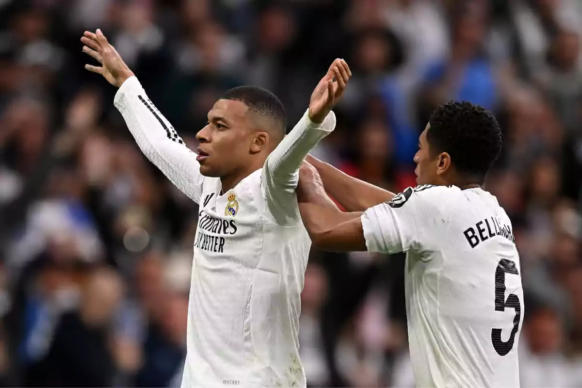 Two players in white uniforms celebrate on the field during a match. Two players in white uniforms celebrate on the field during a match.