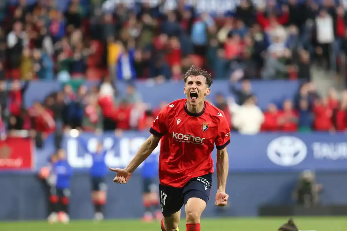 Futbolista celebrando un gol con expresión de euforia en un estadio lleno de aficionados