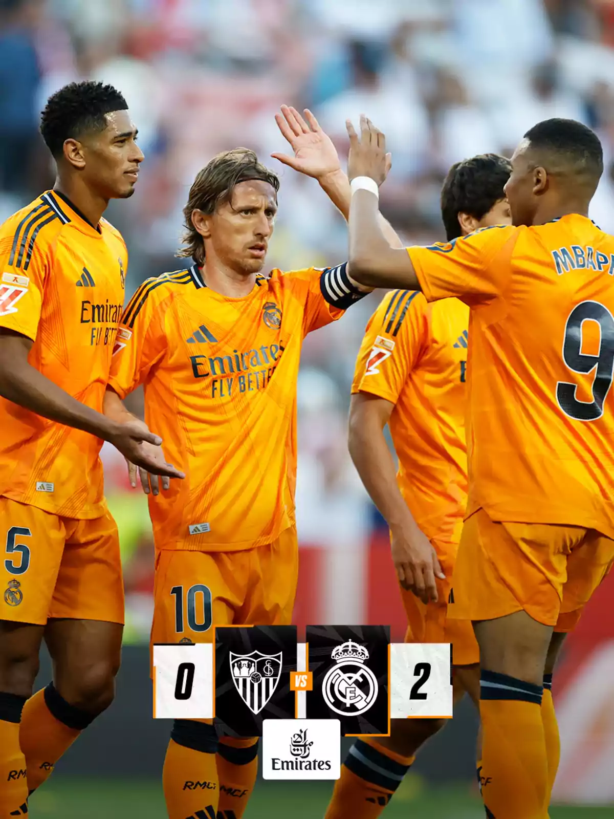 Soccer players in orange uniforms celebrate a victory in a match between Sevilla and Real Madrid, with a score of 0-2 in favor of Real Madrid. Soccer players in orange uniforms celebrate a victory in a match between Sevilla and Real Madrid, with a score of 0-2 in favor of Real Madrid.