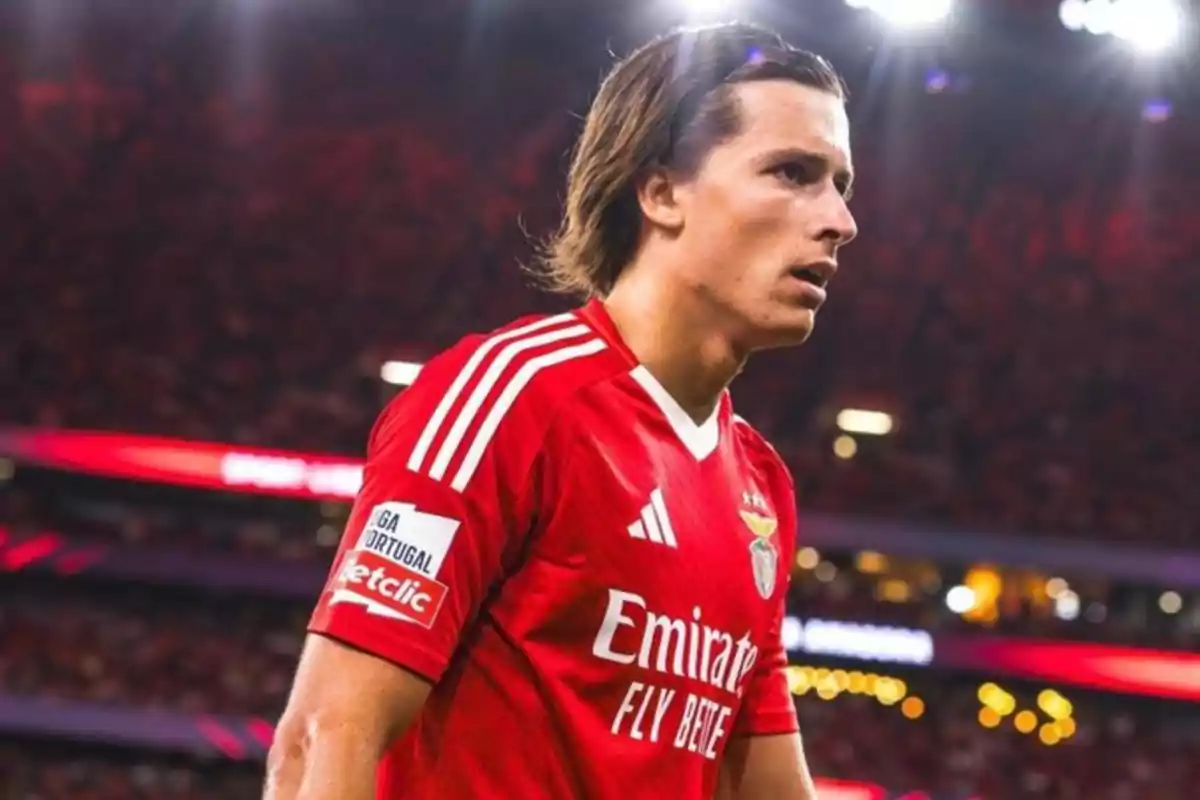 A player in a red jersey in a lit-up stadium. A player in a red jersey in a lit-up stadium.