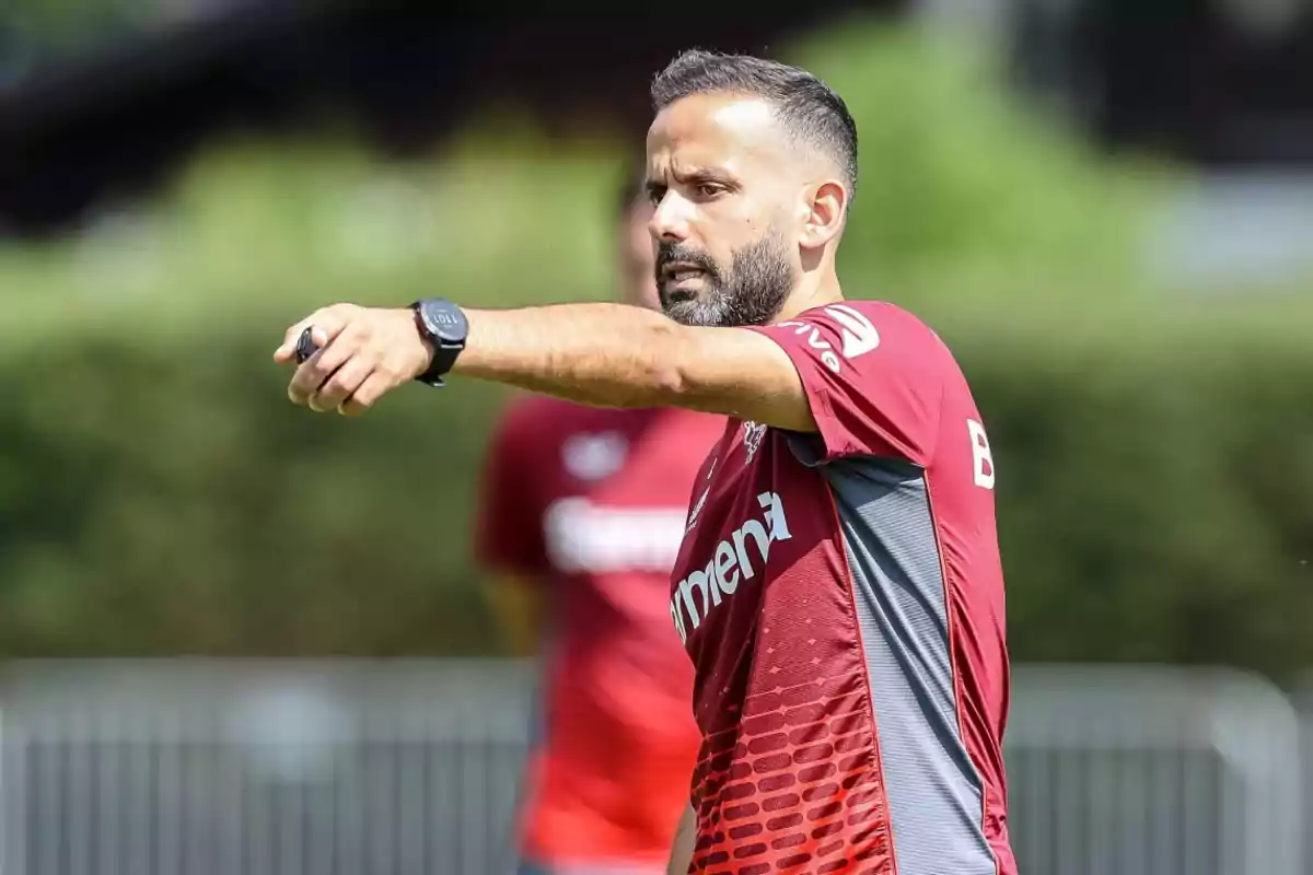 Soccer coach in a red jersey giving instructions on an outdoor field Soccer coach in a red jersey giving instructions on an outdoor field