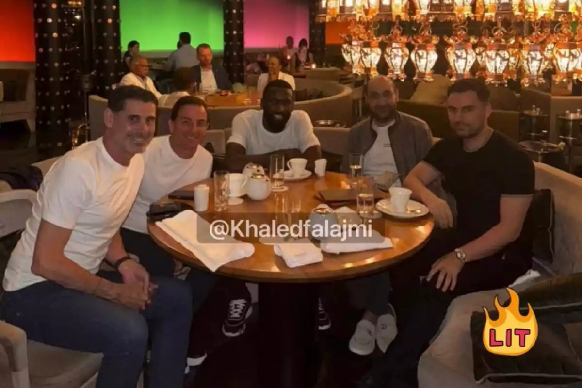 Five men sitting around a round table in an upscale restaurant with hanging lights and coffee cups on the table Five men sitting around a round table in an upscale restaurant with hanging lights and coffee cups on the table