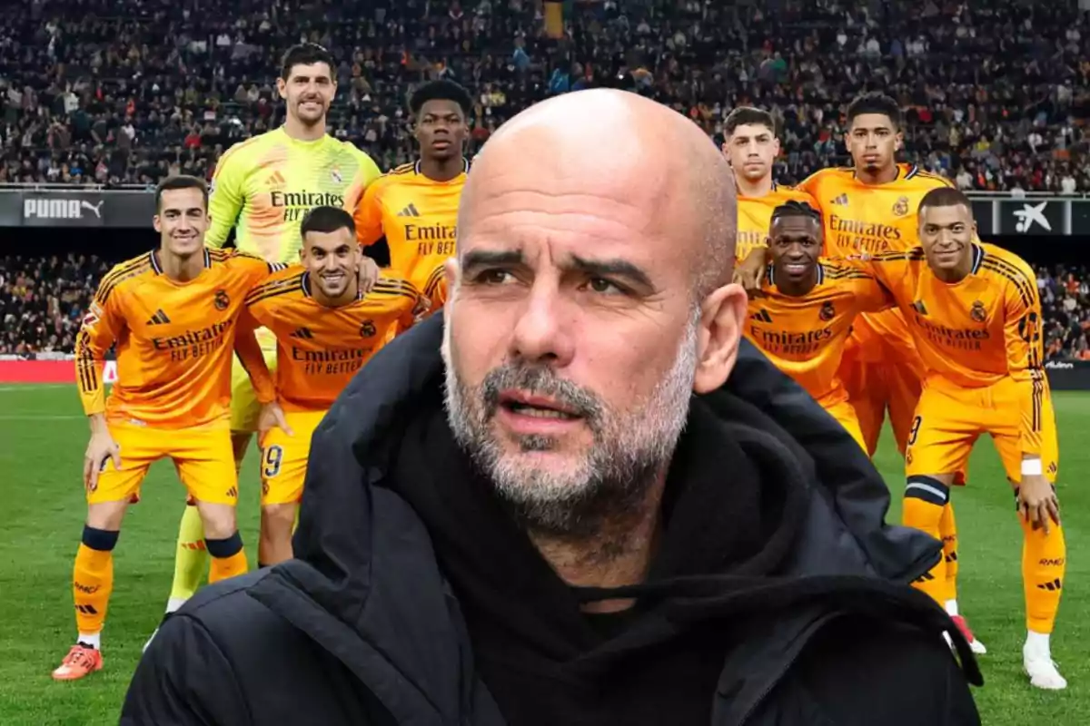 A group of soccer players in orange uniforms posing on the field with a bald man in the foreground.