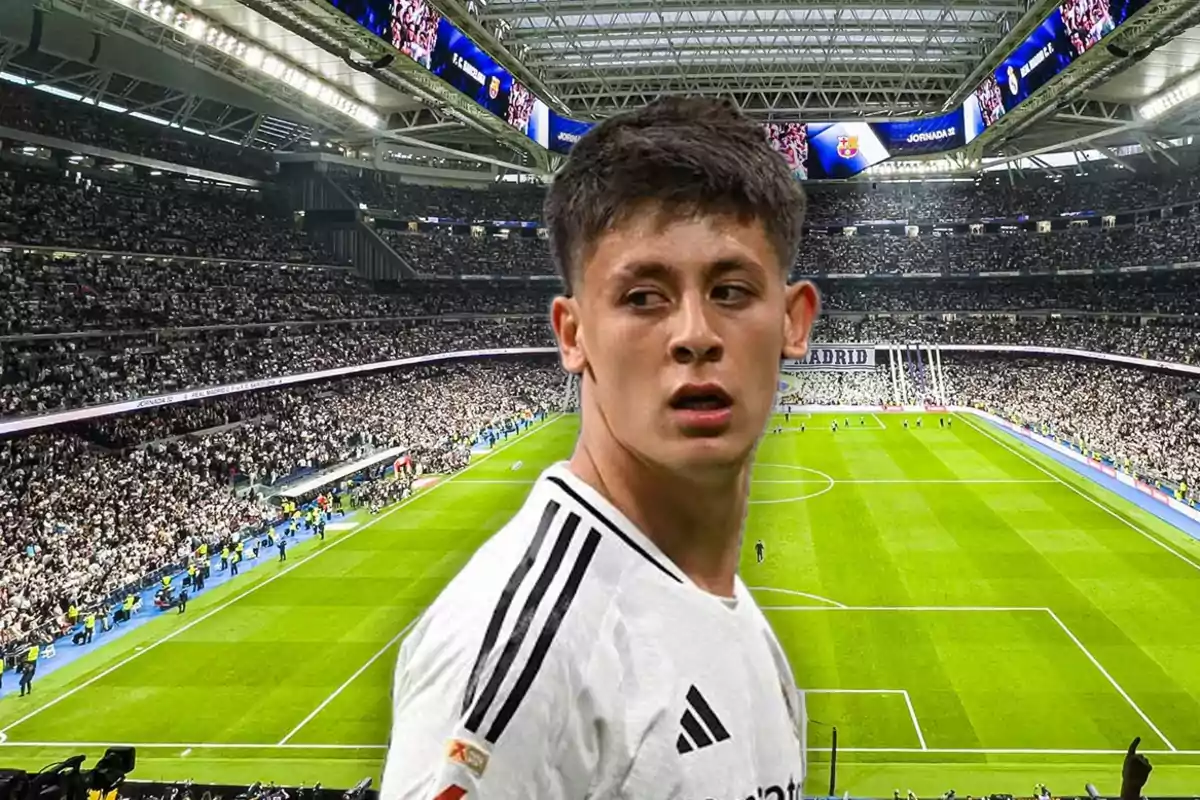 Jugador de fútbol con uniforme blanco en un estadio lleno de aficionados