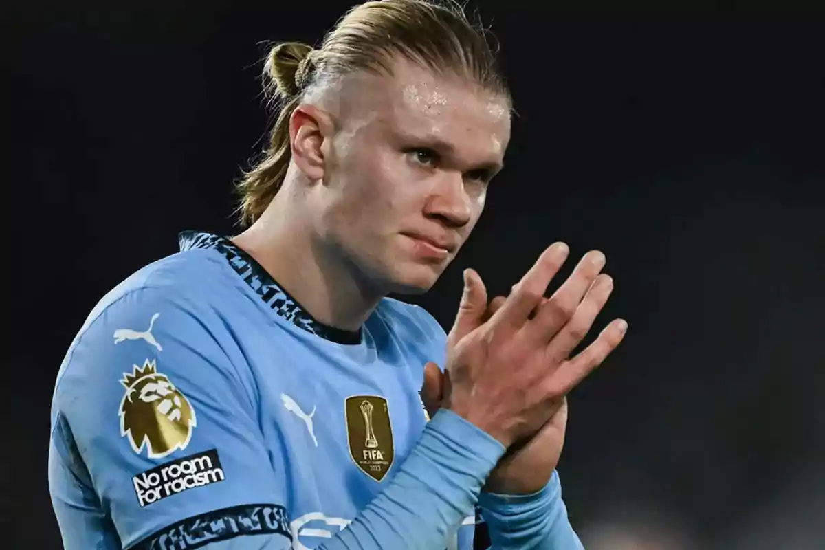 A player in a blue jersey applauds on the field. A player in a blue jersey applauds on the field.