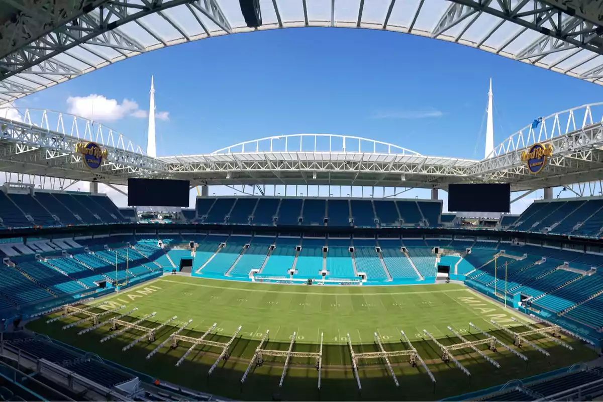 Empty American football stadium with blue stands and a partially covered roof on a sunny day Empty American football stadium with blue stands and a partially covered roof on a sunny day