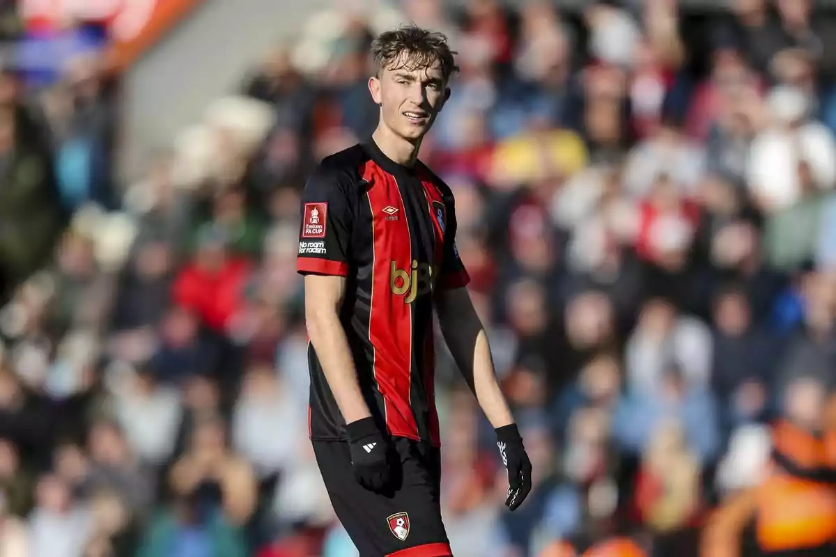 A player in a red and black uniform on the field during a match. A player in a red and black uniform on the field during a match.
