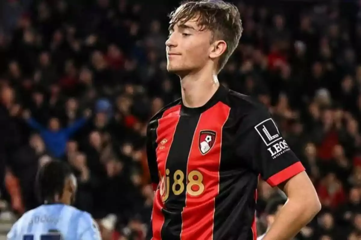 Young player in red and black uniform in a stadium full of spectators. Young player in red and black uniform in a stadium full of spectators.