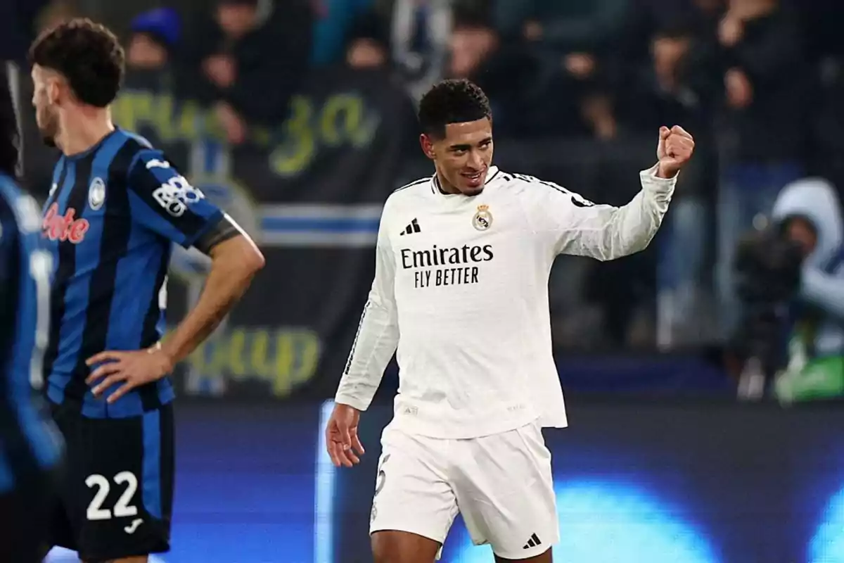 A Real Madrid soccer player celebrates on the field while another player from the opposing team watches.