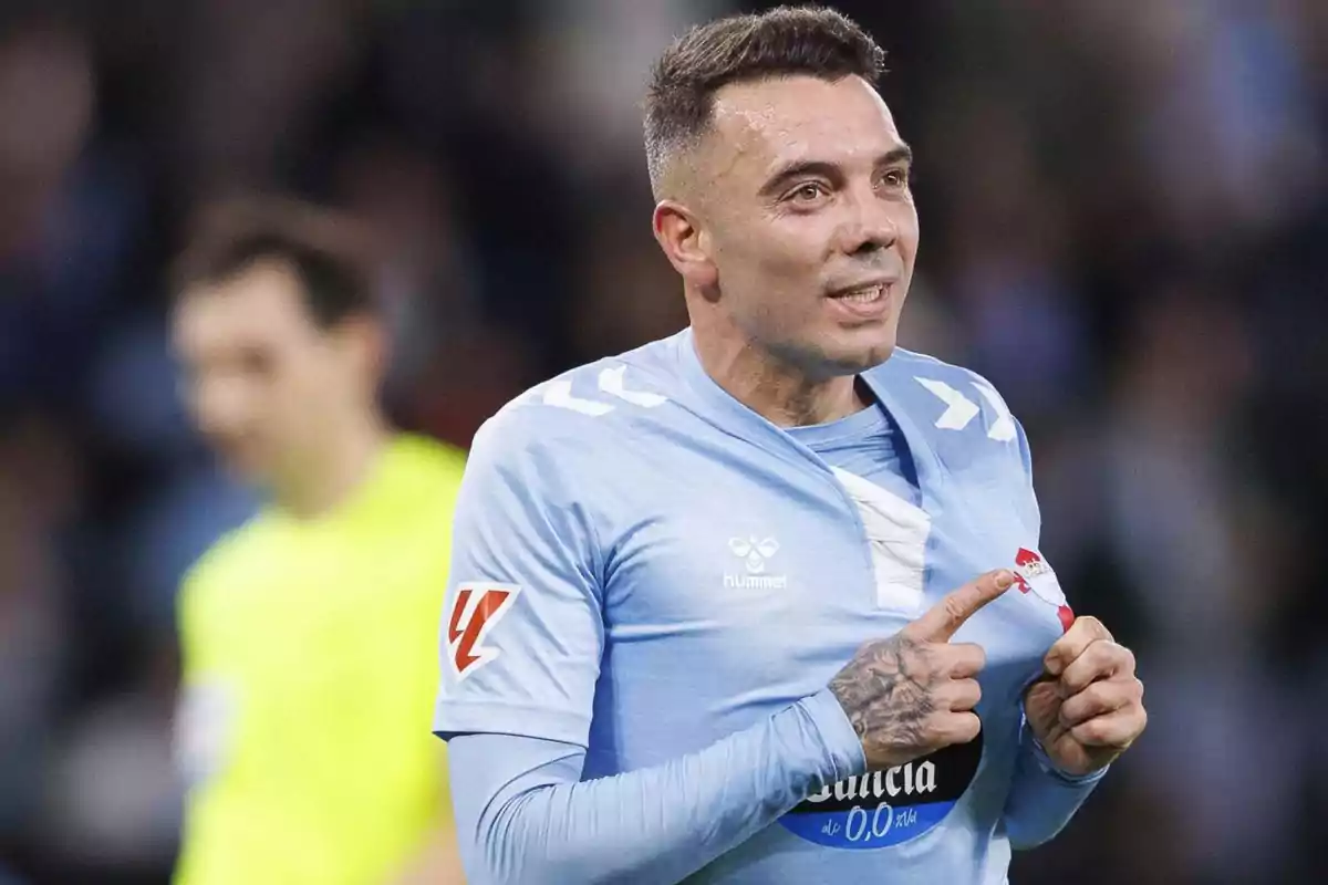 Un jugador de fútbol con uniforme celeste señala el escudo de su camiseta durante un partido. Un jugador de fútbol con uniforme celeste señala el escudo de su camiseta durante un partido.