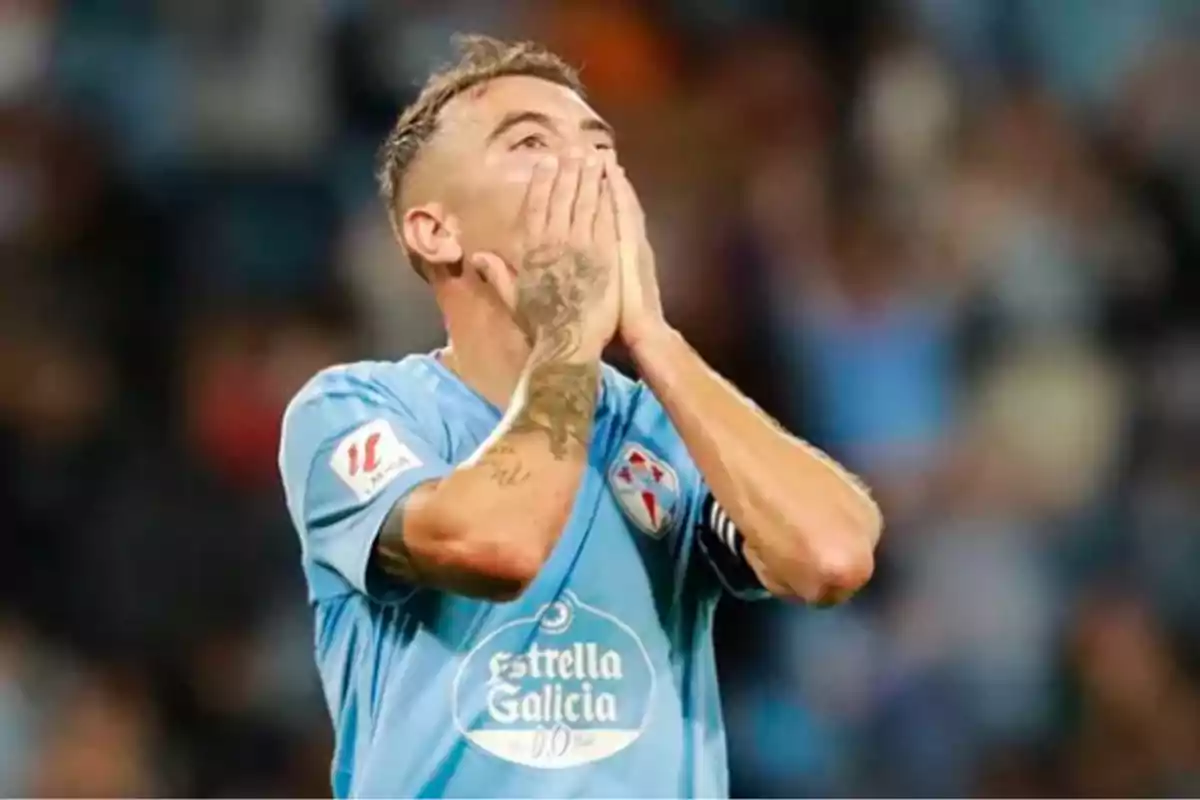 A player in a light blue uniform brings his hands to his face in a gesture of emotion or surprise during a match. A player in a light blue uniform brings his hands to his face in a gesture of emotion or surprise during a match.