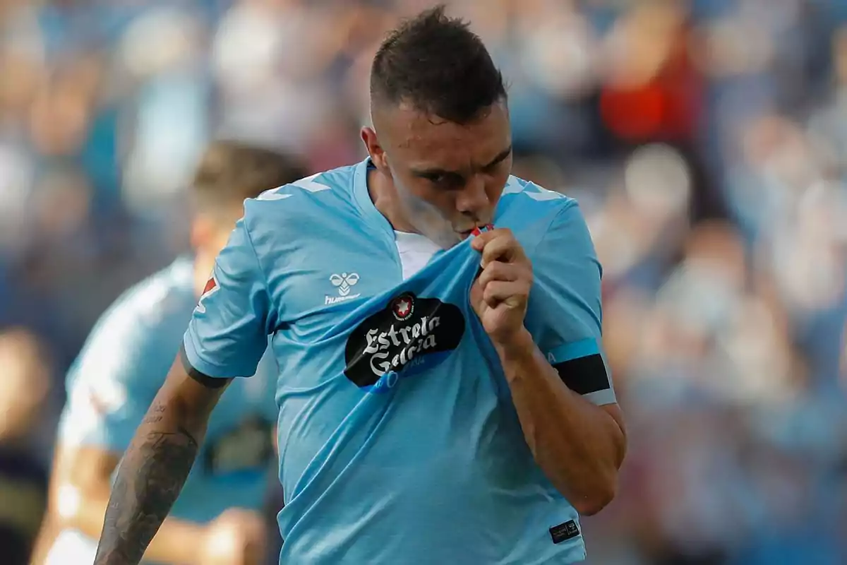 A player kisses the crest on his light blue jersey during a match. A player kisses the crest on his light blue jersey during a match.