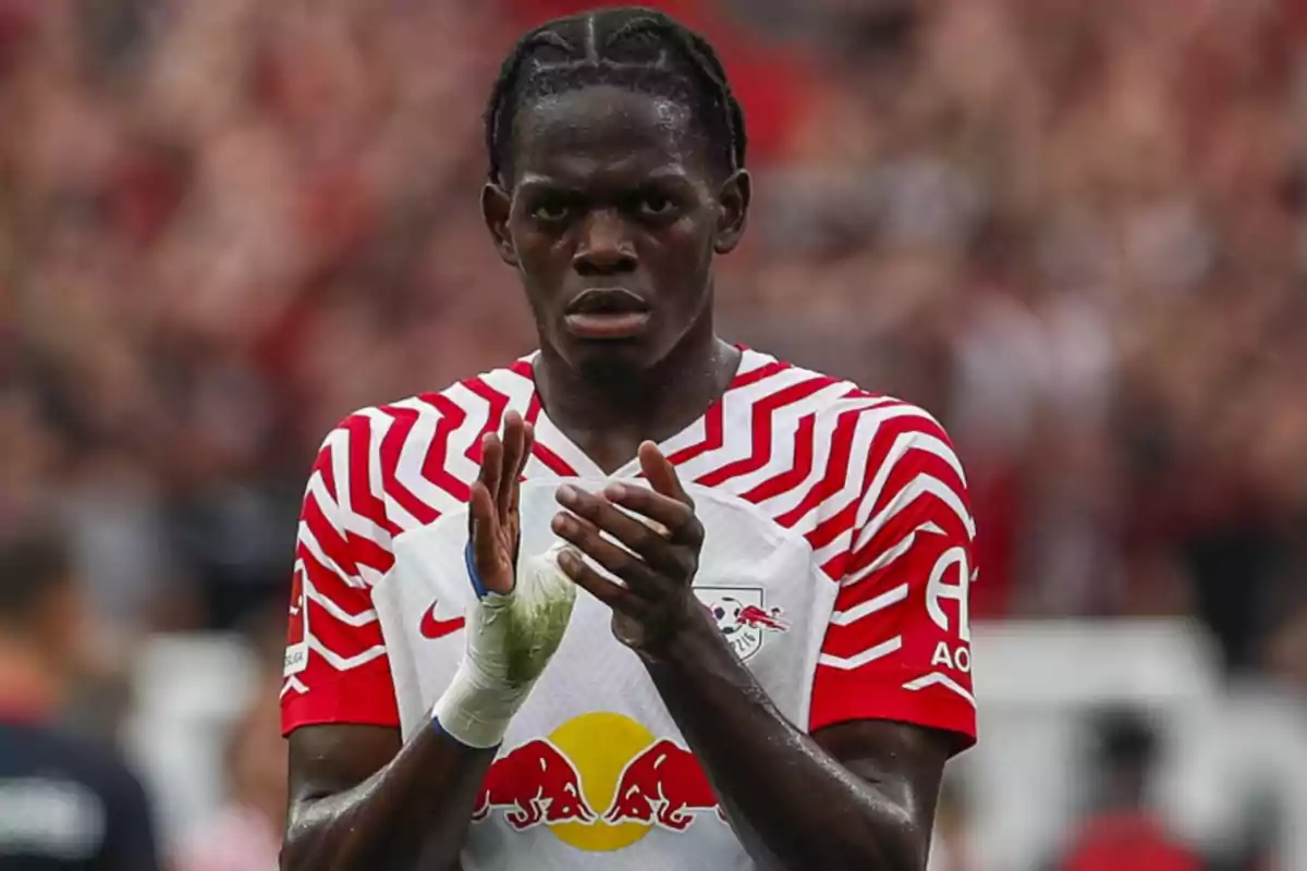 A soccer player in a white and red uniform applauds on the field. A soccer player in a white and red uniform applauds on the field.