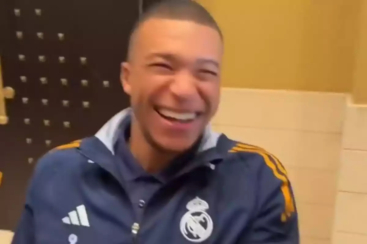 Smiling person wearing a dark blue sports jacket with white and gold details. Smiling person wearing a dark blue sports jacket with white and gold details.