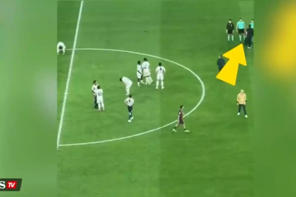 Soccer players on the field during a match, with a group of referees and a coach in the top right corner. Soccer players on the field during a match, with a group of referees and a coach in the top right corner.