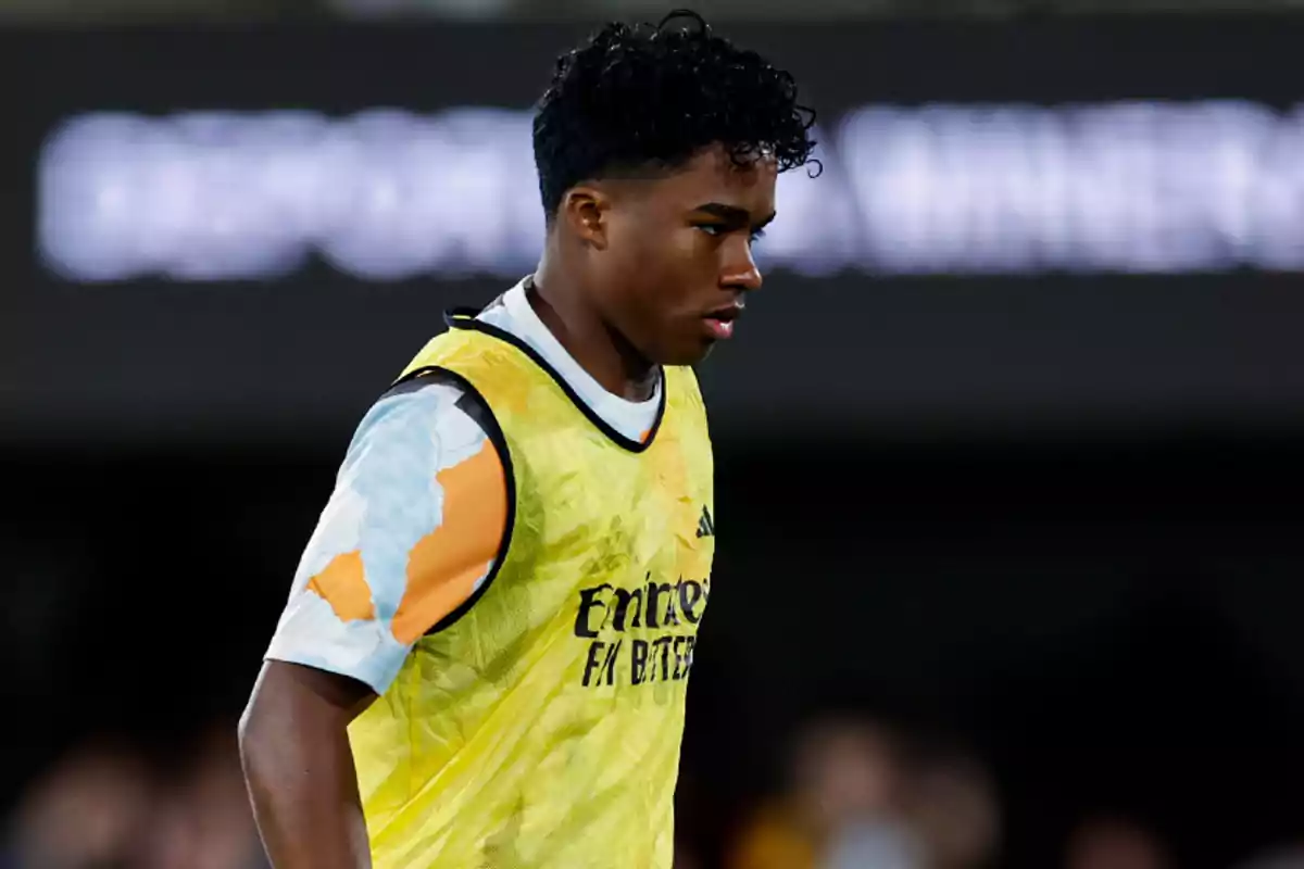 A soccer player in a yellow training vest on the field. A soccer player in a yellow training vest on the field.