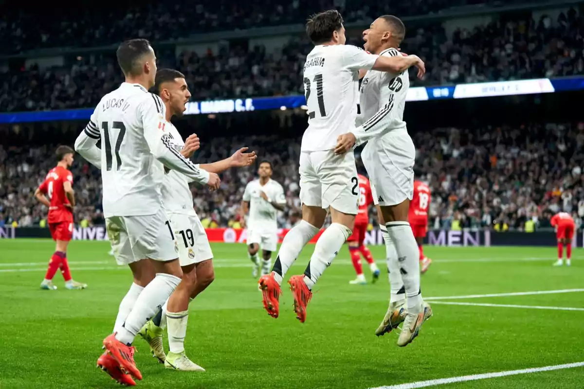 Jugadores de fútbol celebrando un gol en un estadio lleno de espectadores.