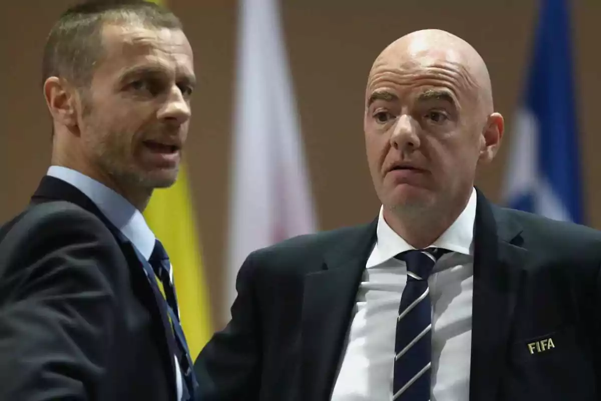 Dos hombres en trajes oscuros conversan en un evento formal, uno de ellos lleva una insignia de la FIFA. Dos hombres en trajes oscuros conversan en un evento formal, uno de ellos lleva una insignia de la FIFA.