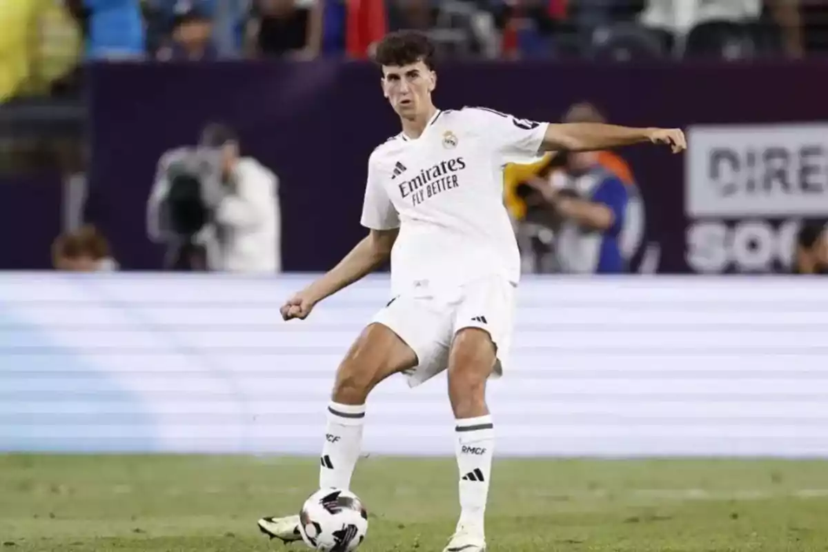 Un jugador de fútbol con uniforme blanco está en el campo controlando el balón durante un partido. Un jugador de fútbol con uniforme blanco está en el campo controlando el balón durante un partido.