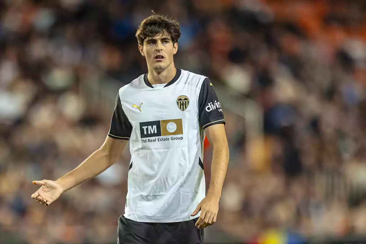 A player in a black and white uniform on the field during a match. A player in a black and white uniform on the field during a match.