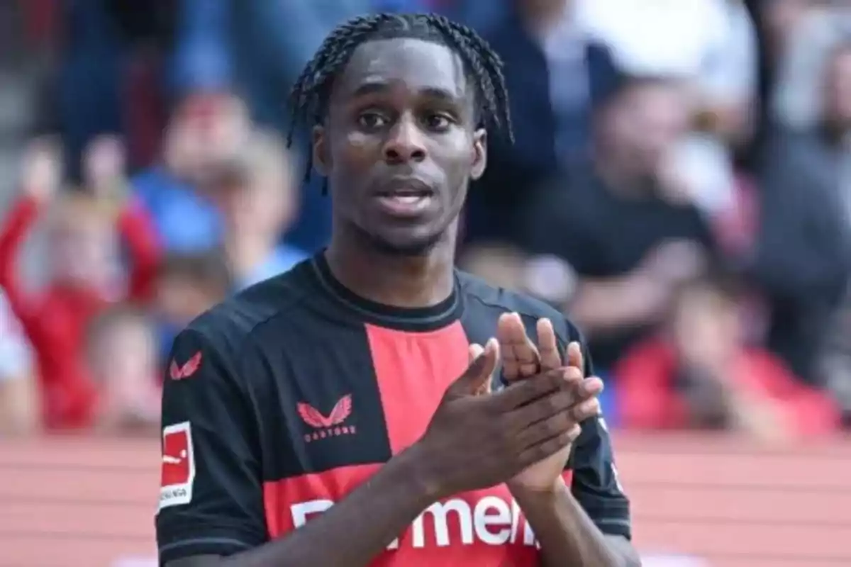 A soccer player applauding on the field in a black and red jersey. A soccer player applauding on the field in a black and red jersey.