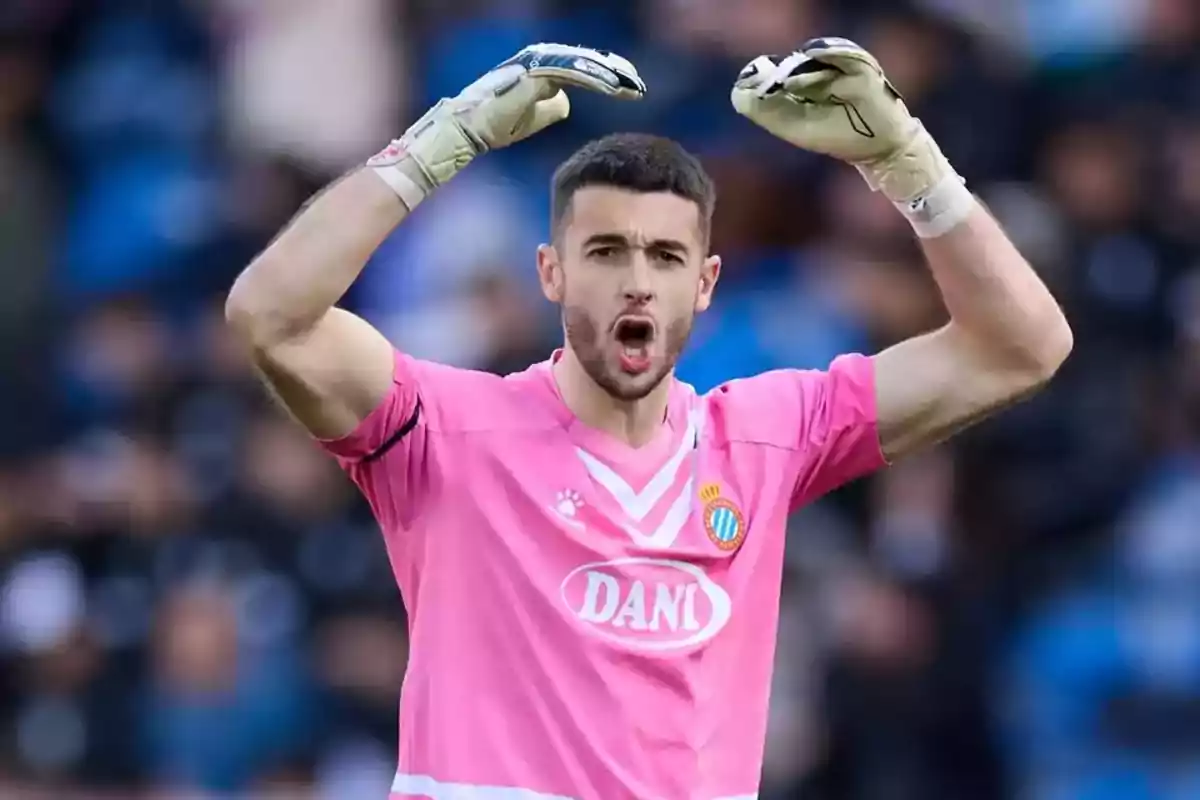 Soccer goalkeeper in a pink uniform and gloves raising his arms and shouting in a stadium Soccer goalkeeper in a pink uniform and gloves raising his arms and shouting in a stadium