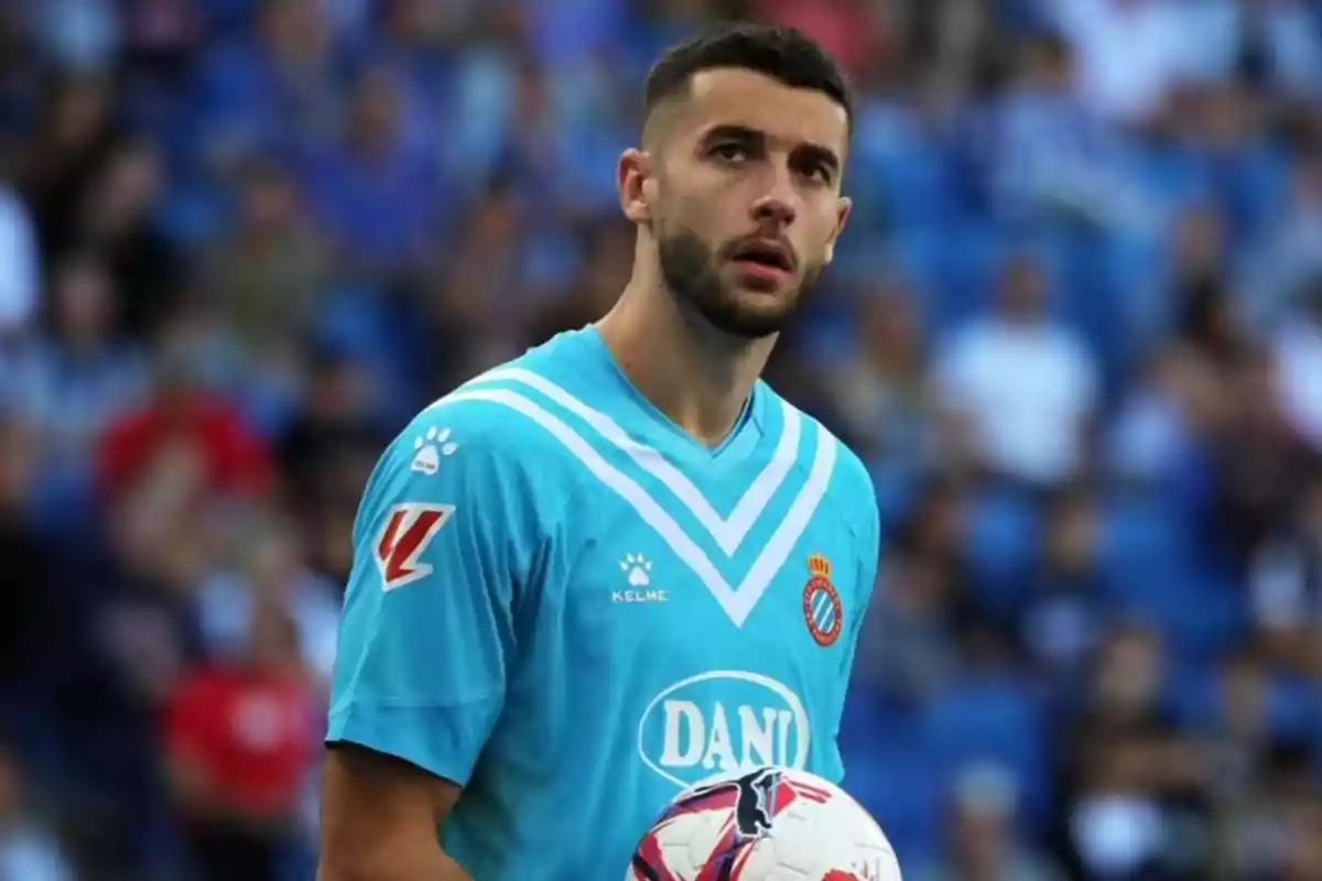 A player in a light blue uniform holds a ball in a stadium full of spectators. A player in a light blue uniform holds a ball in a stadium full of spectators.