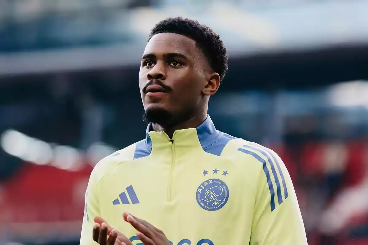Un jugador de fútbol con uniforme de entrenamiento del Ajax, de pie en un estadio. Un jugador de fútbol con uniforme de entrenamiento del Ajax, de pie en un estadio.