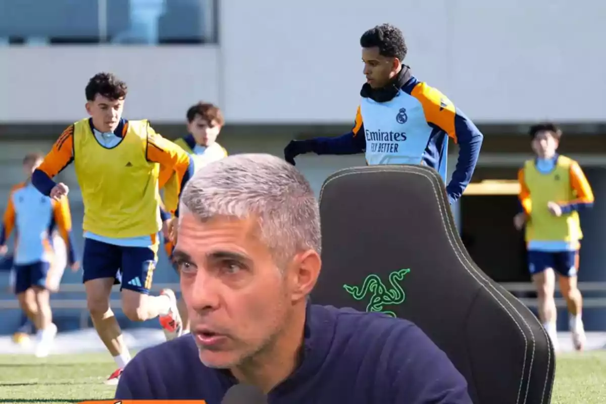 A man speaking into a microphone with soccer players training in the background.