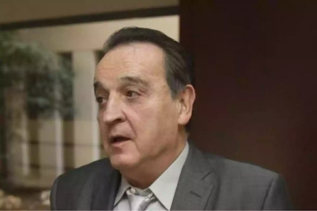 Un hombre de mediana edad con traje gris y corbata clara en un entorno interior. Un hombre de mediana edad con traje gris y corbata clara en un entorno interior.