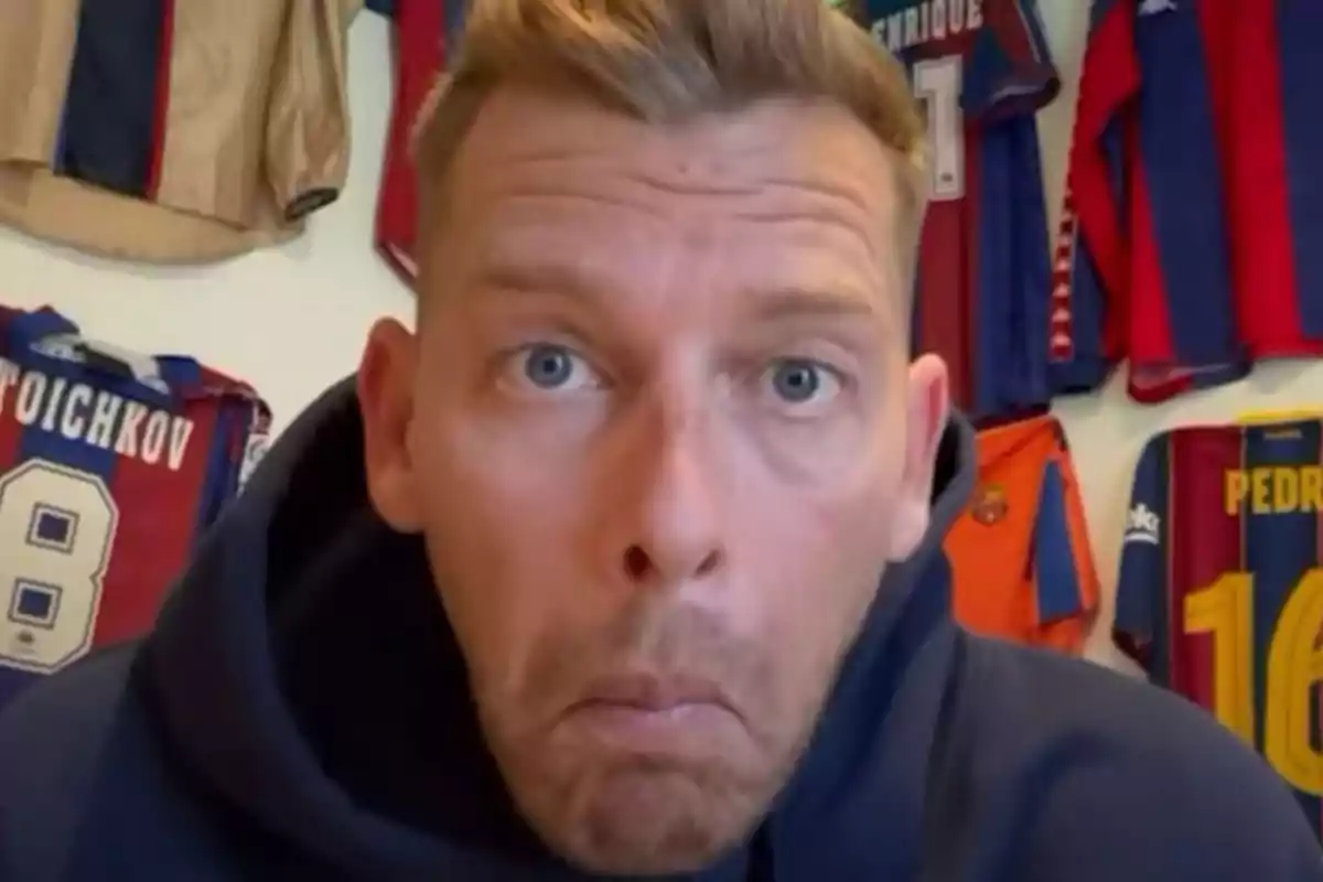 A man with a surprised expression in front of a wall with framed soccer jerseys. A man with a surprised expression in front of a wall with framed soccer jerseys.