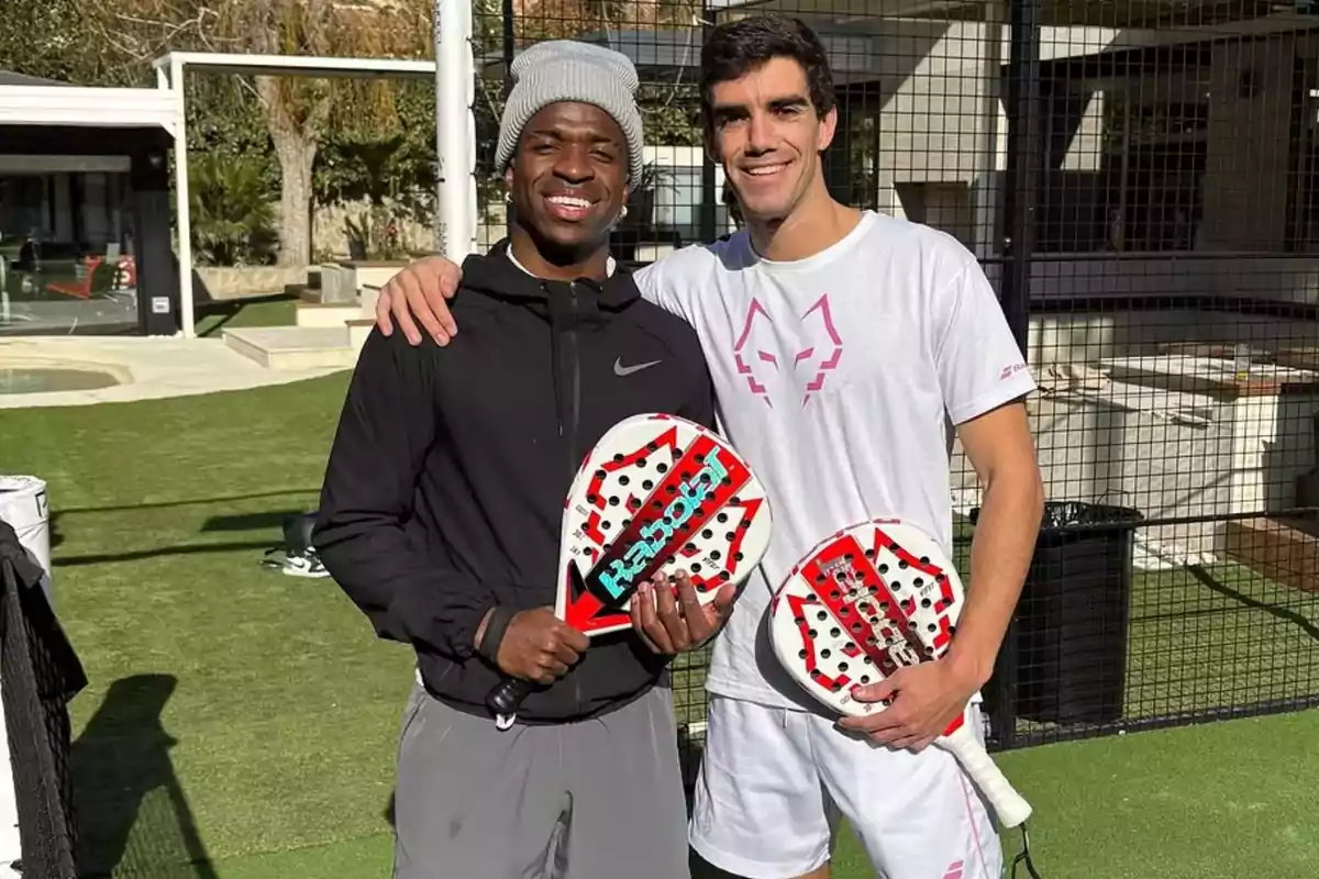 Dos personas sonríen y posan juntas en una cancha de pádel mientras sostienen palas de pádel