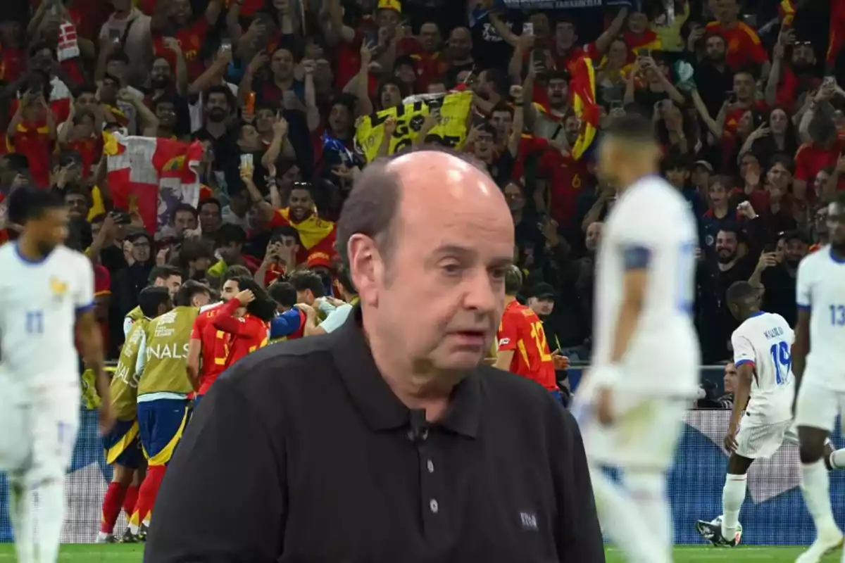 A man with a serious expression in the foreground while in the background a group of players celebrates in a stadium full of fans.