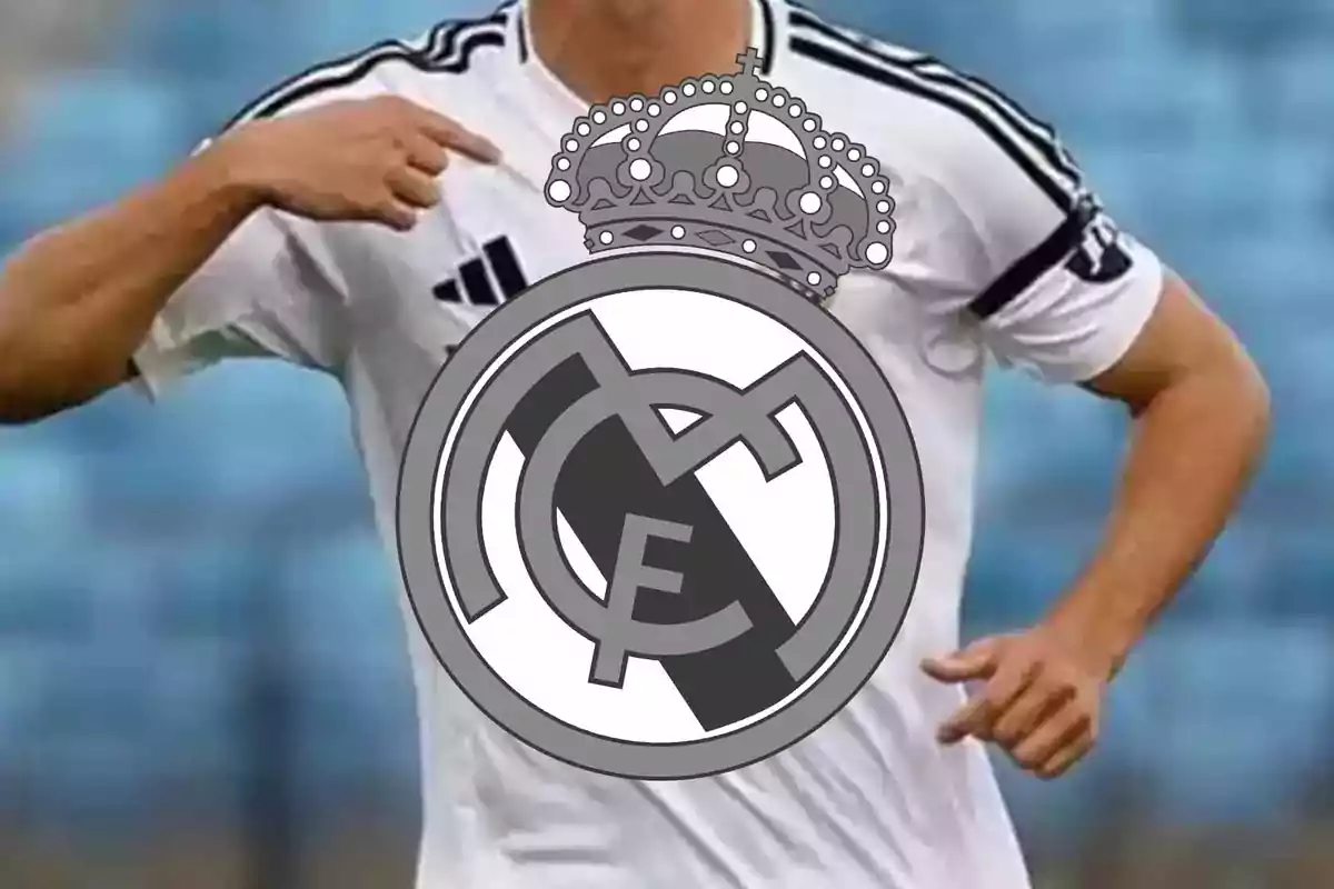 Football player in a white jersey pointing at the Real Madrid crest.