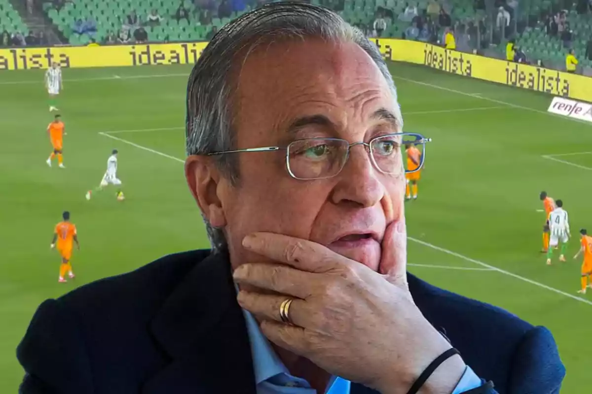 A man with glasses and a thoughtful expression appears in the foreground, while a soccer match is seen in the background at a stadium.