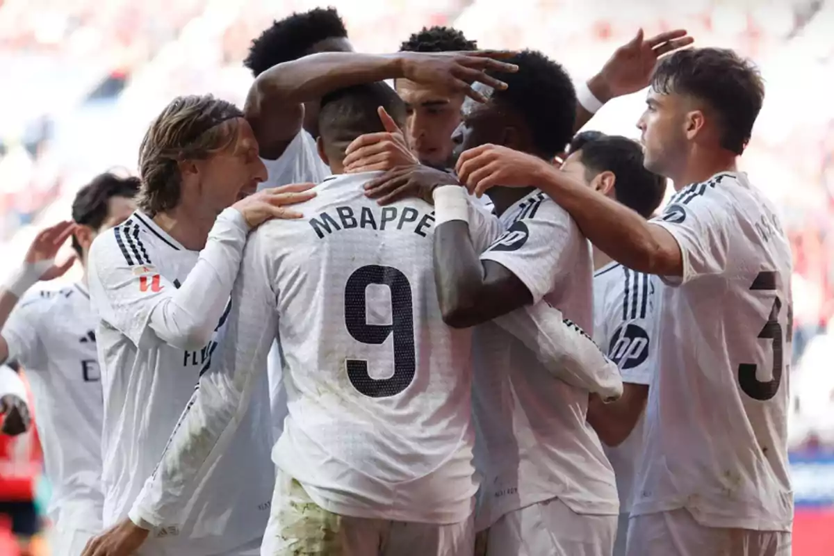 A group of players in white uniforms celebrating together on the field.