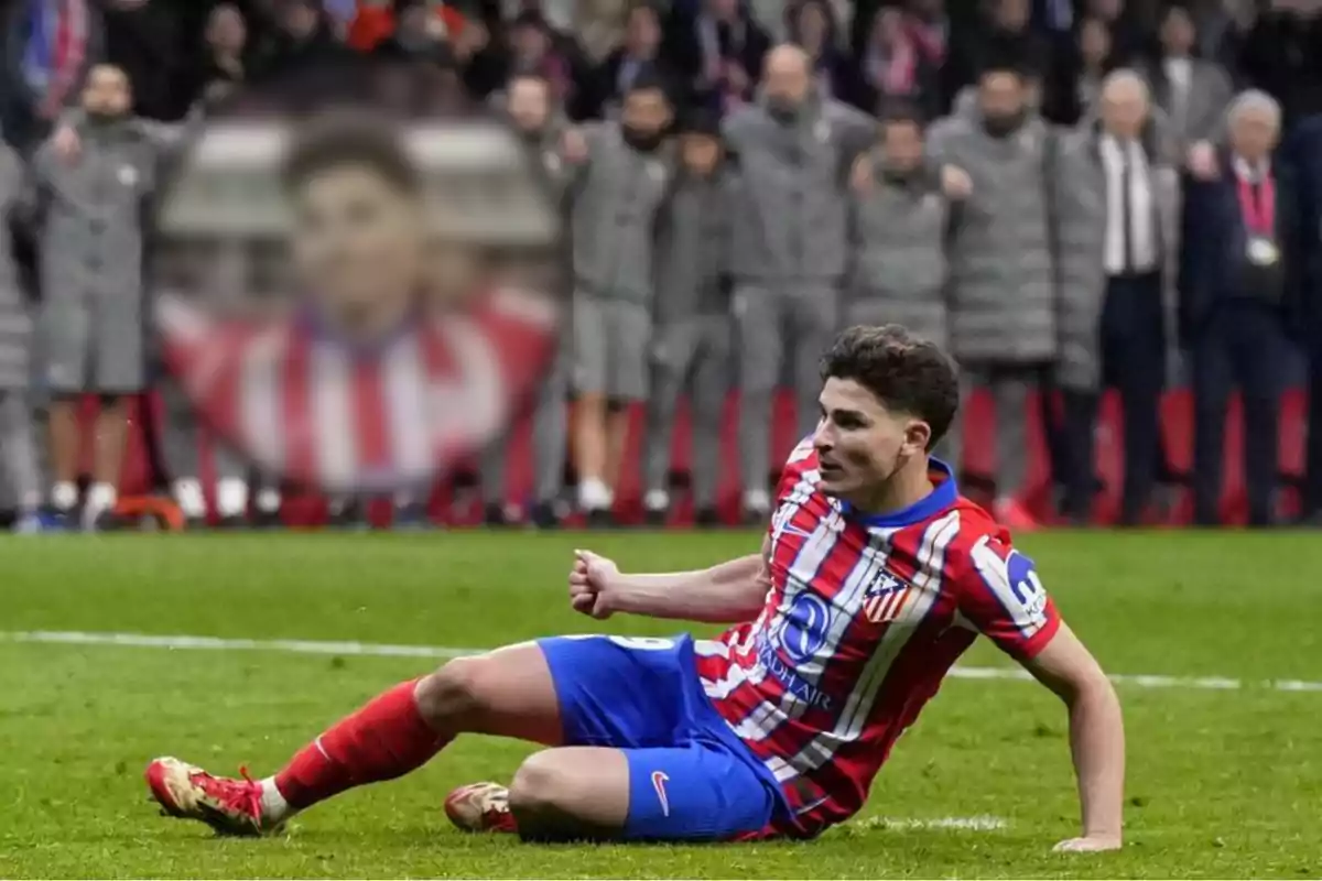 An Atlético de Madrid player celebrates on the field while the crowd watches from the stands.