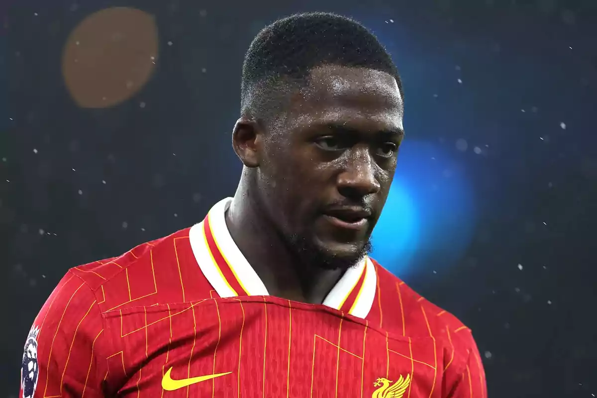 Un jugador de fútbol con camiseta roja y detalles amarillos en un campo de juego. Un jugador de fútbol con camiseta roja y detalles amarillos en un campo de juego.