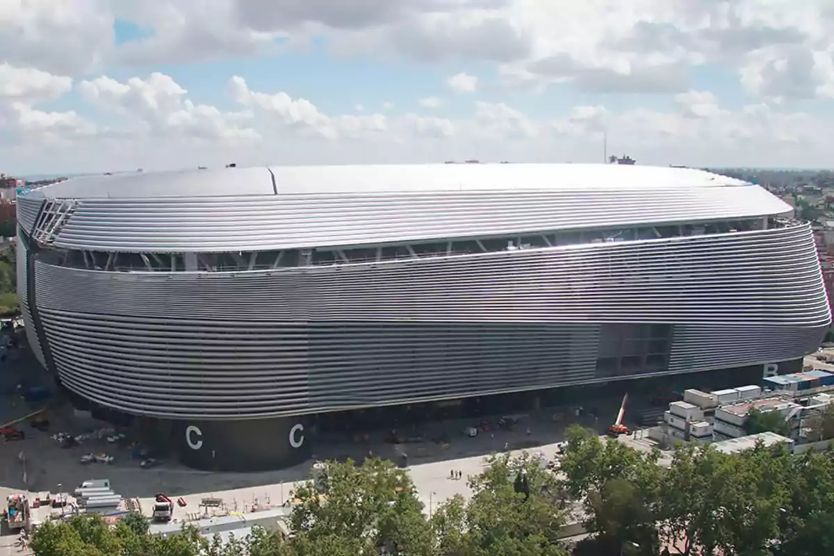 A modern stadium with a curved, metallic architectural design under a partly cloudy sky. A modern stadium with a curved, metallic architectural design under a partly cloudy sky.