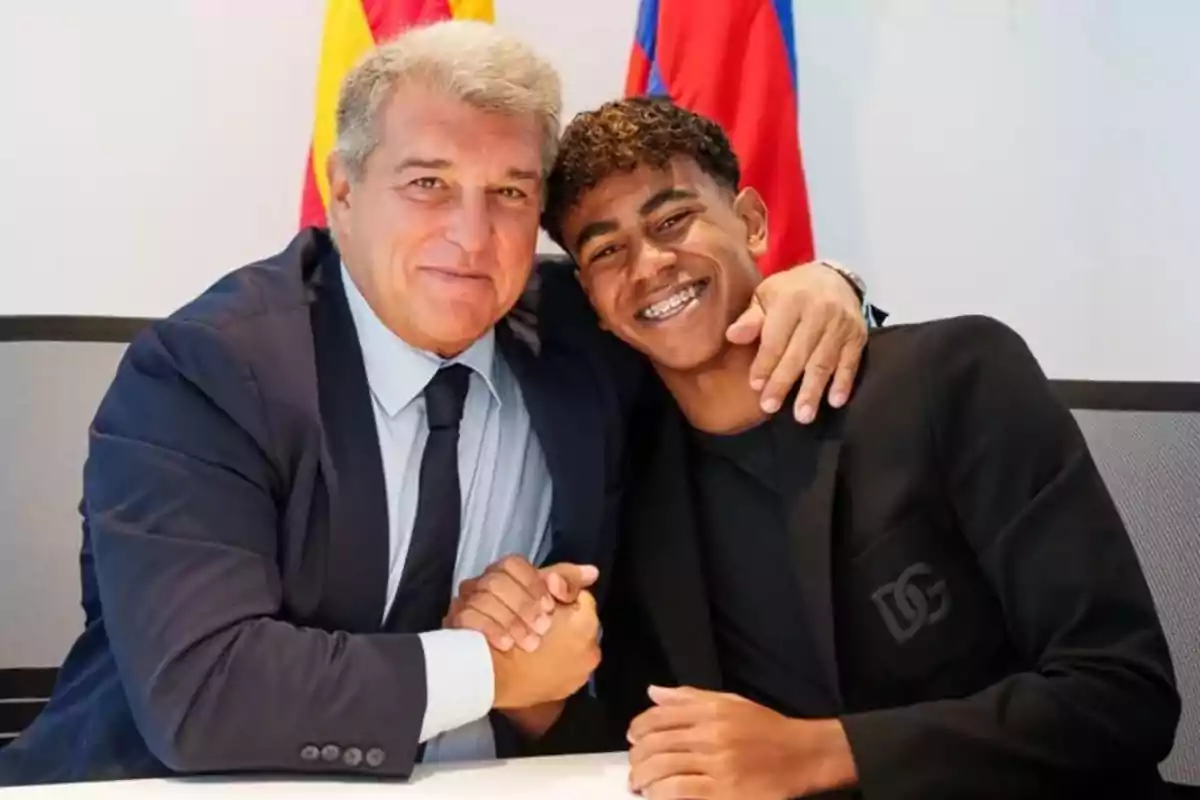 Dos personas sonríen y posan juntas mientras se dan la mano en una oficina con banderas de fondo Dos personas sonríen y posan juntas mientras se dan la mano en una oficina con banderas de fondo