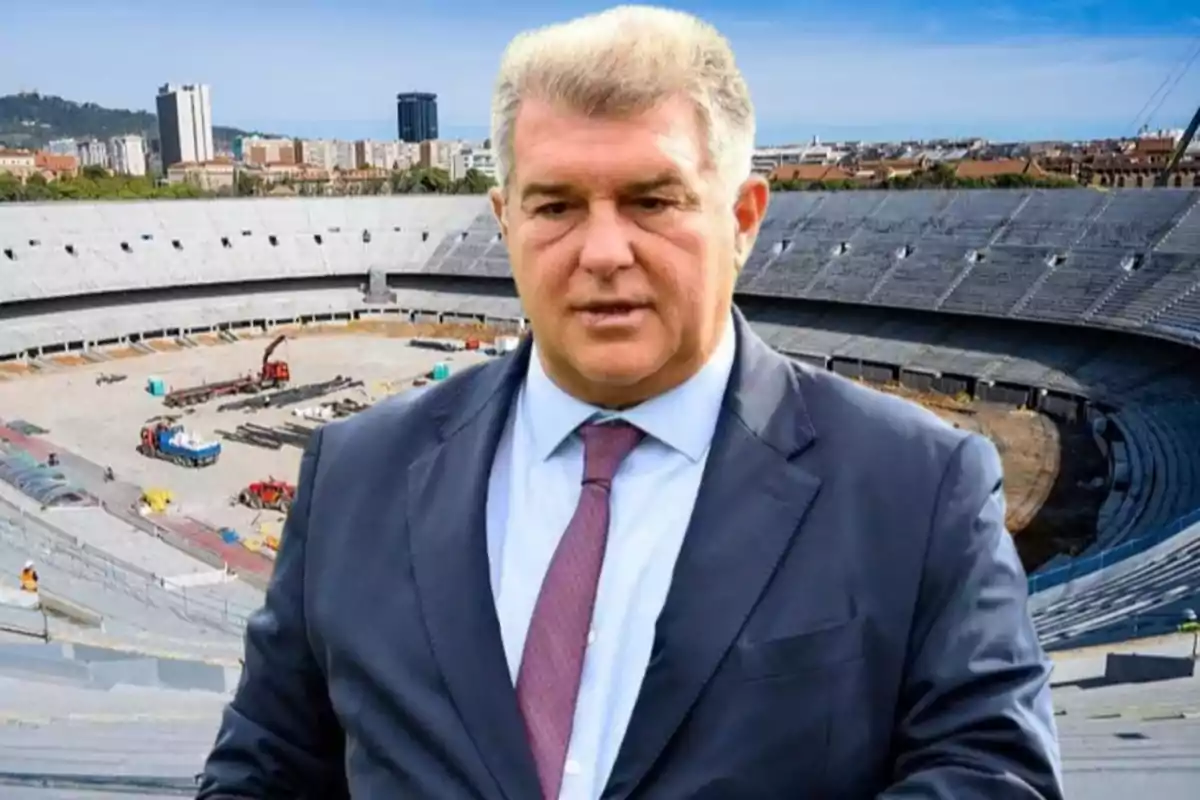 A man in a suit in front of a stadium under construction.